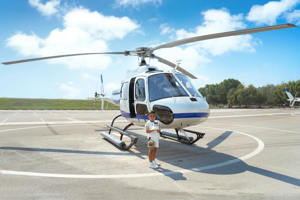 흰색과 파란색 헬리콥터를 배경으로 케이크를 들고 있는 행복한 아이.