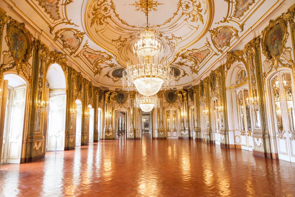 정교하게 장식된 천장, 커다란 샹들리에, 아치형 창문, 광택이 나는 나무 바닥이 있는 화려한 연회장.