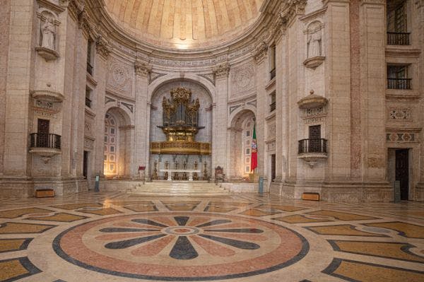 전면에 커다란 파이프 오르간, 대리석 기둥, 복잡한 벽 조각, 타일 바닥이 있는 웅장하고 화려한 대성당의 내부.