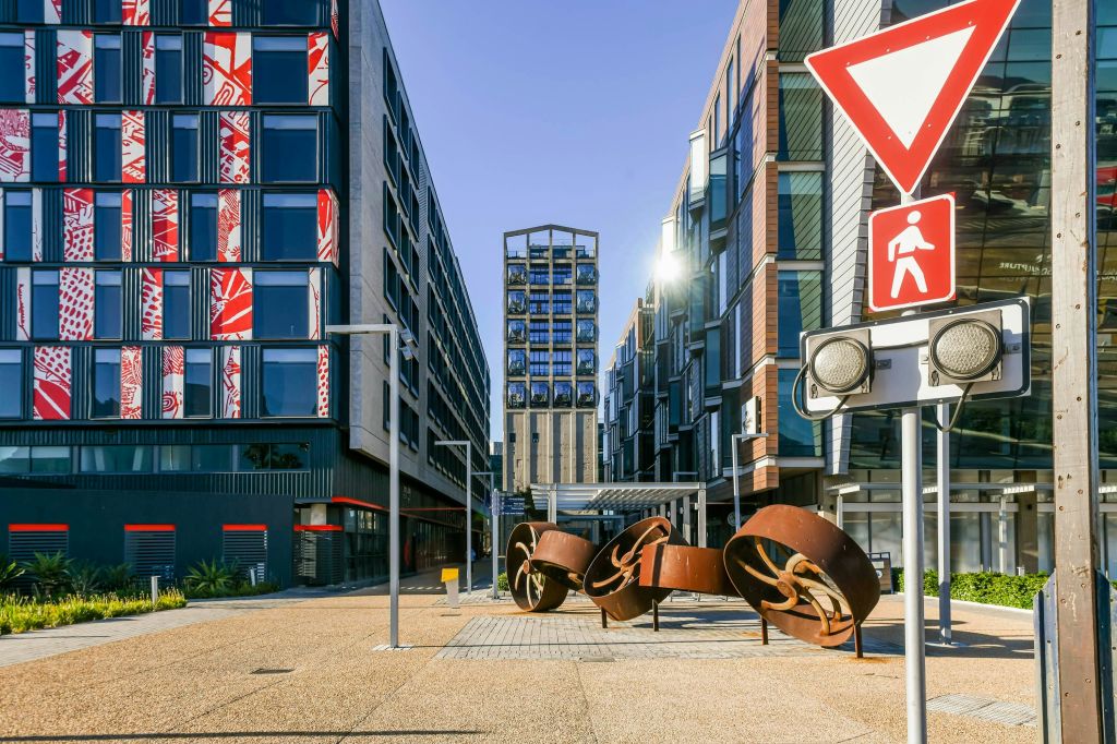 현대적인 건물, 추상적인 조각, 거리 표지판, 맑고 푸른 하늘이 있는 도시 풍경.