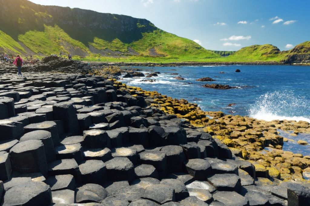 푸른 언덕과 푸른 하늘을 배경으로 바다로 이어지는 육각형의 현무암 기둥.