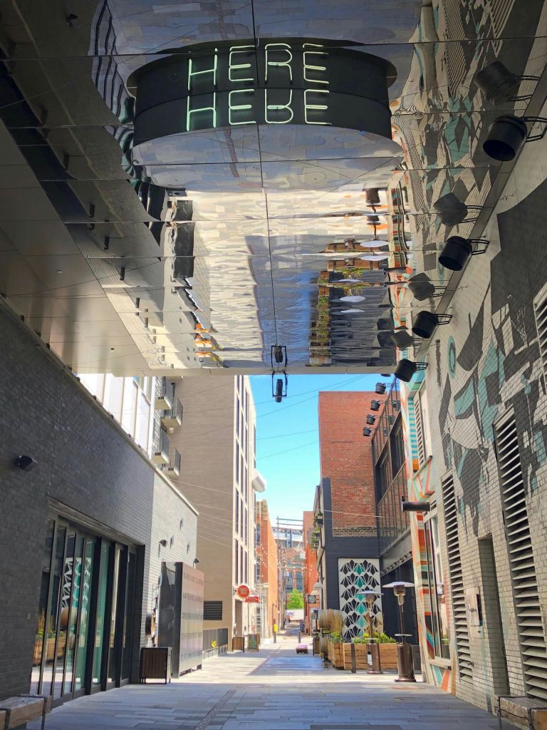 벽돌과 페인트로 칠한 벽, 머리 위 반사, 위 '헤베' 라고 적힌 표지판이 있는 좁은 도심 속 골목길.