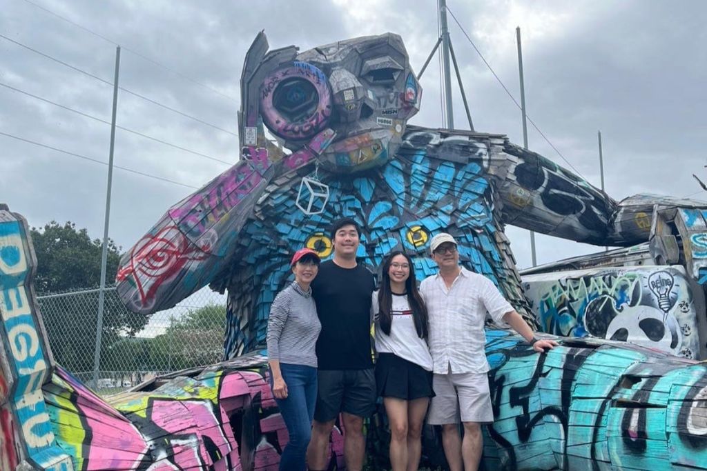 마이애미 3-in-1 시티 투어에 참여한 한 가족이 윈우드의 거대한 예술 작품 앞에서 포즈를 취하고 있습니다.