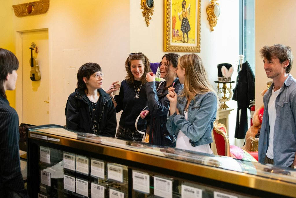 네 명의 사람이 유리 카운터 주변에 모여서 대화를 나누고 활기차게 보입니다.