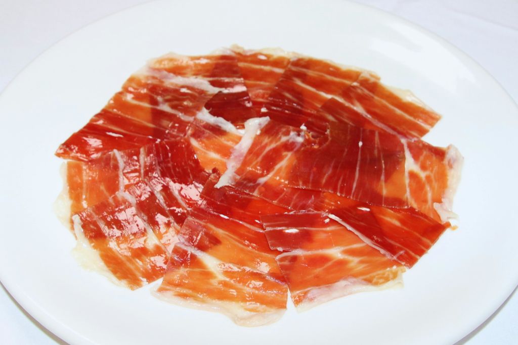 흰색 접시에 얇게 썬 경화 햄이 배열되어 있습니다.