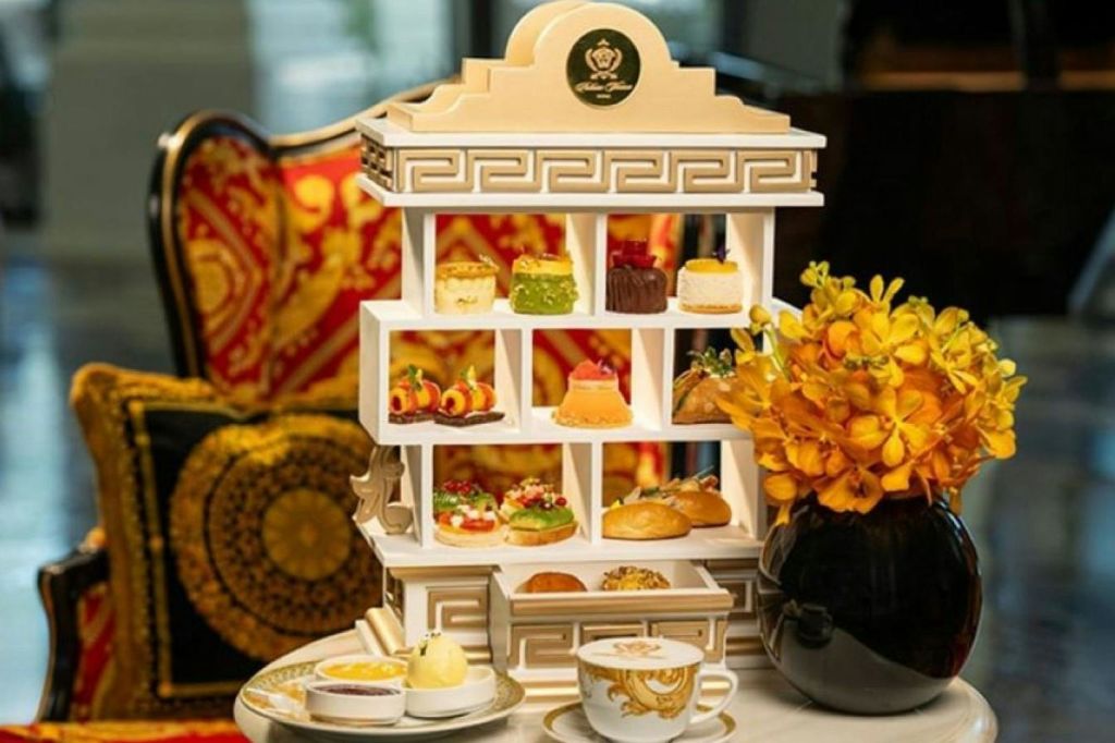 대리석 테이블에 층계 페이스트리, 차 한 잔, 노란색 꽃이 놓인 고급스러운 애프터눈 티 세트.