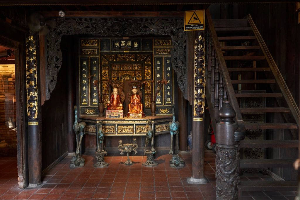 나무 계단 옆에 조각된 나무와 정교한 디테일로 둘러싸인 황금 장식과 조각상이 있는 화려한 제단입니다.