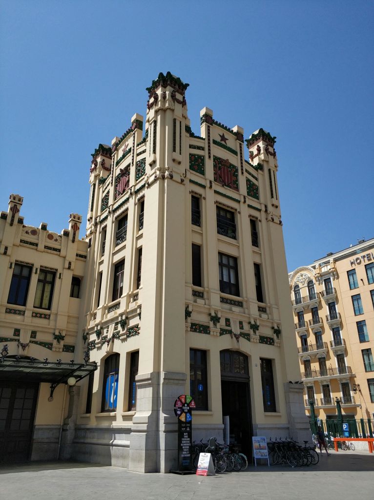 맑고 푸른 하늘 아래 '호텔' 이라는 이름의 또 다른 높은 건물 근처에 장식 요소가 있는 높고 화려한 건물이 있습니다.