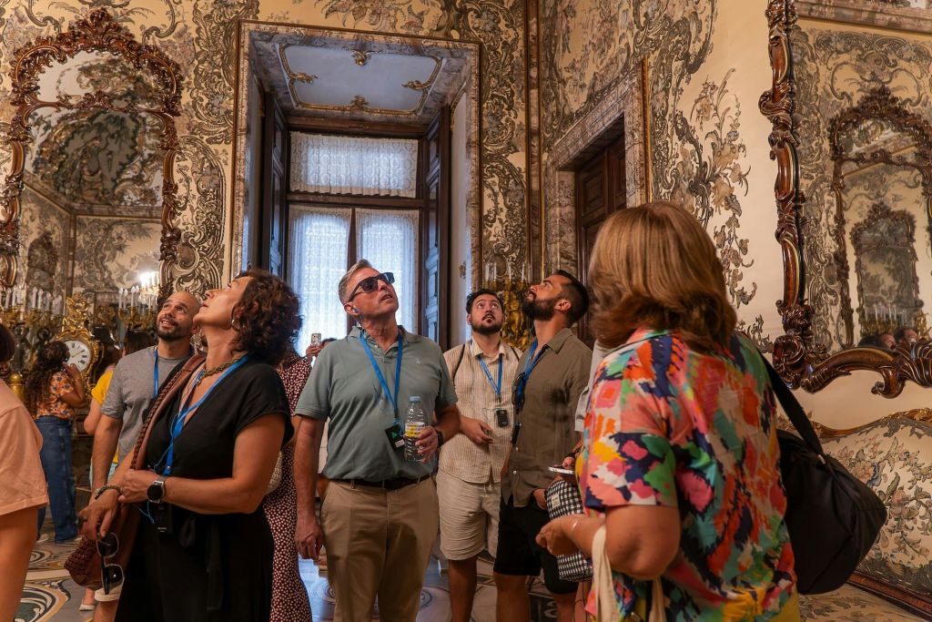 랜야드와 가이드 장치를 착용한 일행이 정교하게 꾸며진 방 안의 화려하고 장식적인 벽과 천장을 올려다보고 있습니다.