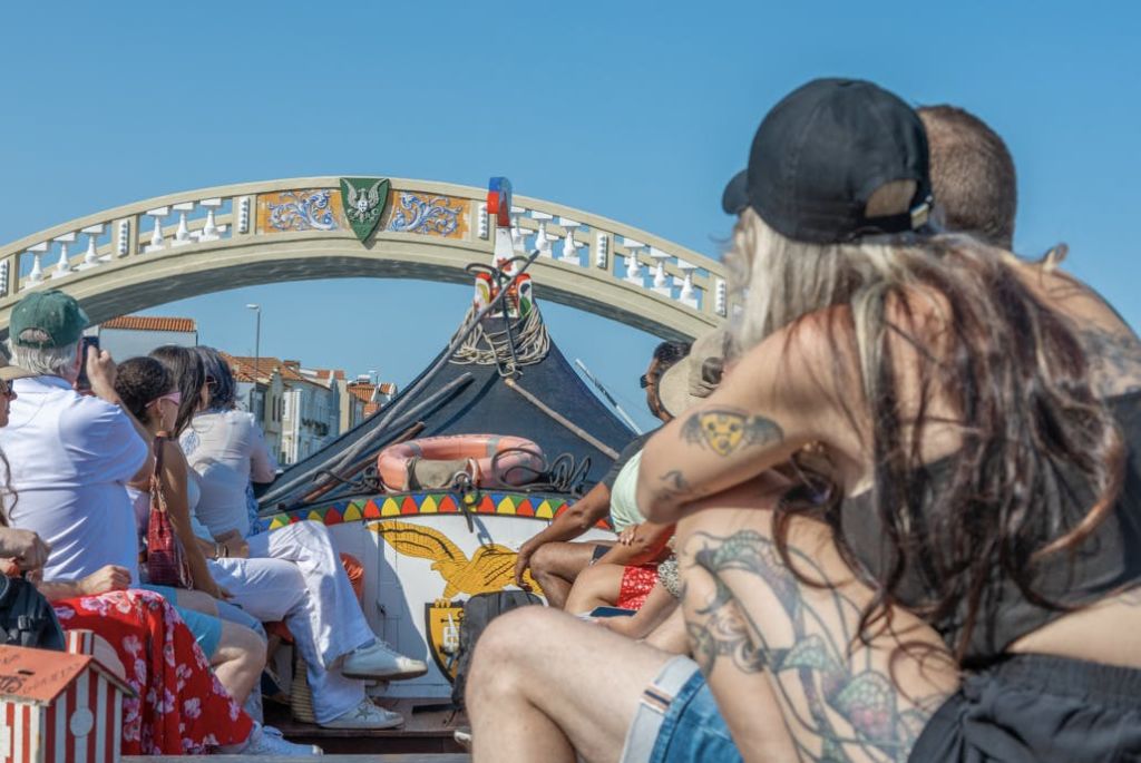 화창하고 화창한 날, 화려한 장식이 돋보이는 보트에 앉아 장식된 다리 아래로 지나가는 사람들.