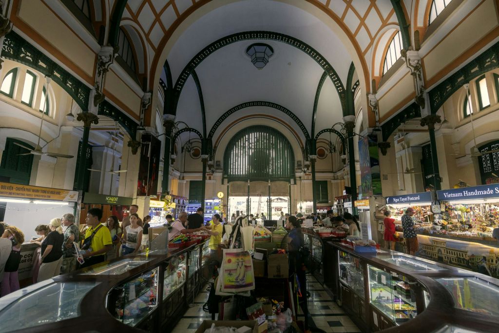 아치형 천장과 상품을 파는 다양한 가판대가 있는 실내 시장. 사람들은 물건을 걷고 탐색합니다.