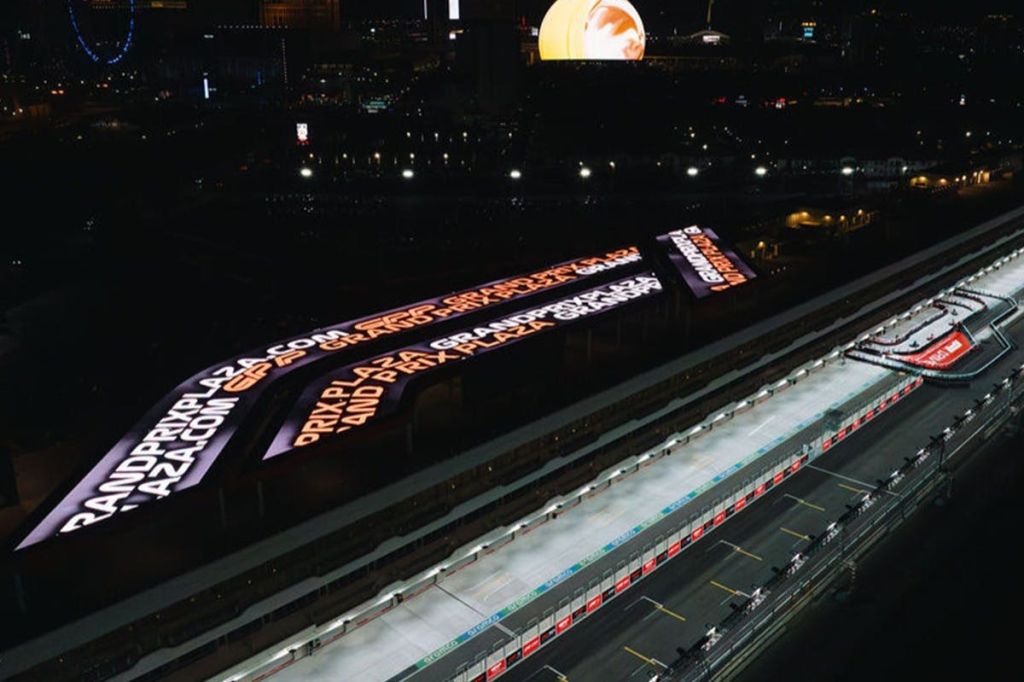 여러 색으로 텍스트를 표시하는 대형 디지털 스크린이 있는 야간에 조명된 경마장의 공중 전망.