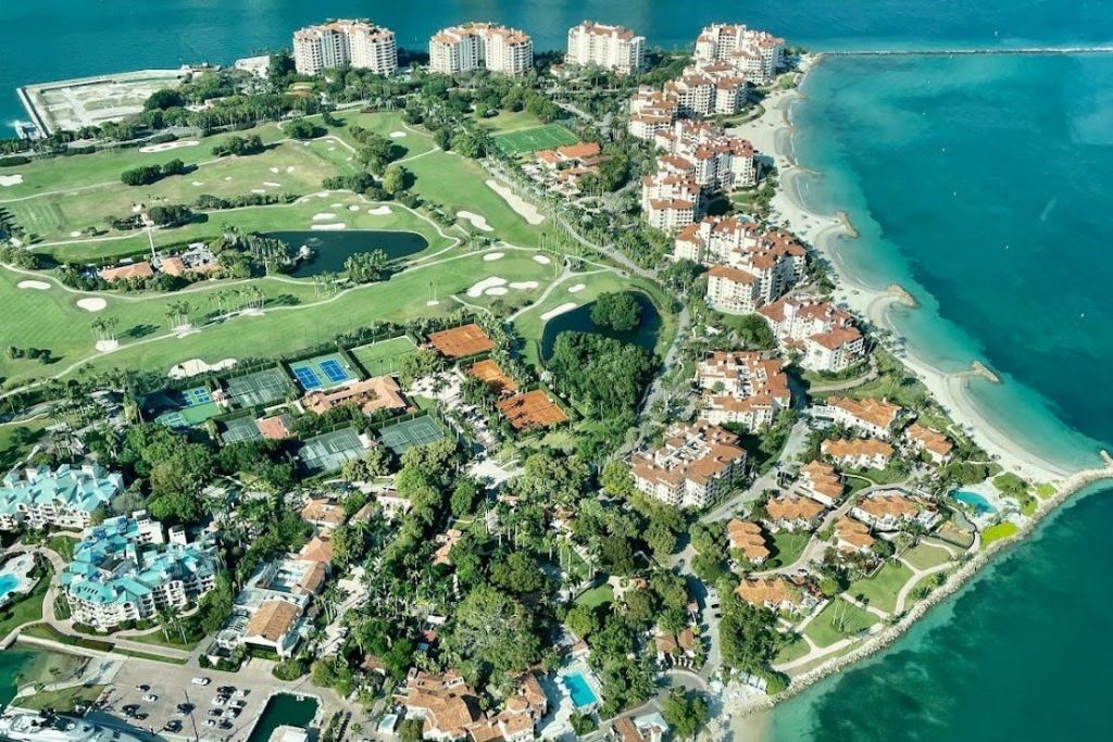 주거 건물, 골프 코스, 테니스 코트, 울창한 녹지, 청록색 바다가 있는 해안 지역의 공중 전망.