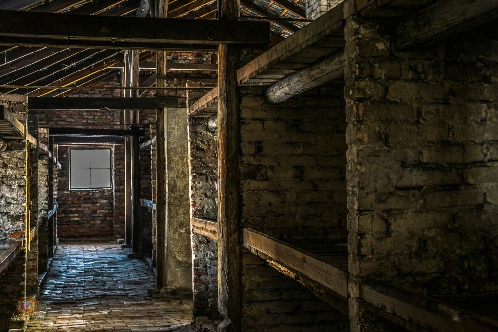 나무 대들보와 선반이 있는 오래된 벽돌 건물의 내부에는 작은 창문과 돌 바닥이 있습니다.