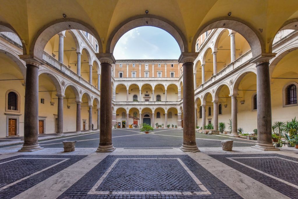 역사적인 건물의 내부 안뜰에는 아치형 통로, 기둥, 타일 바닥이 있는 중앙의 개방형 공간이 있습니다.