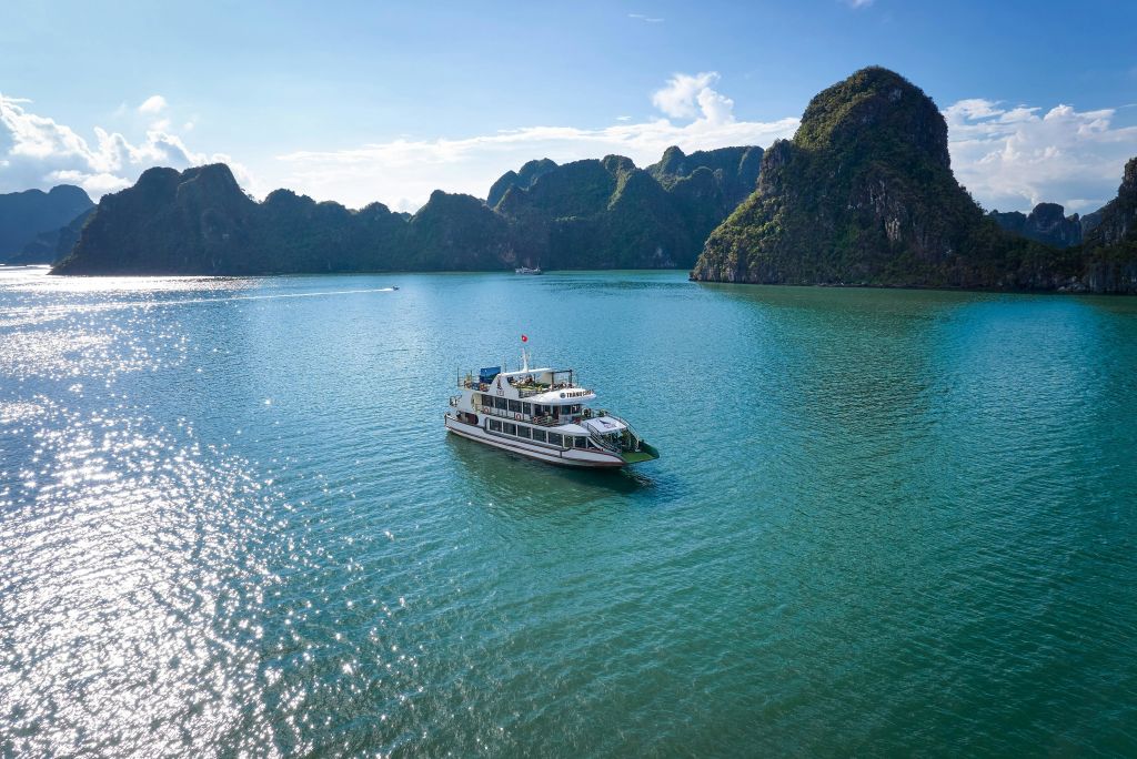 맑고 푸른 하늘 아래 울창하고 바위투성이의 섬으로 둘러싸인 잔잔한 청록색 바다에서 보트를 타고 항해해보세요.
