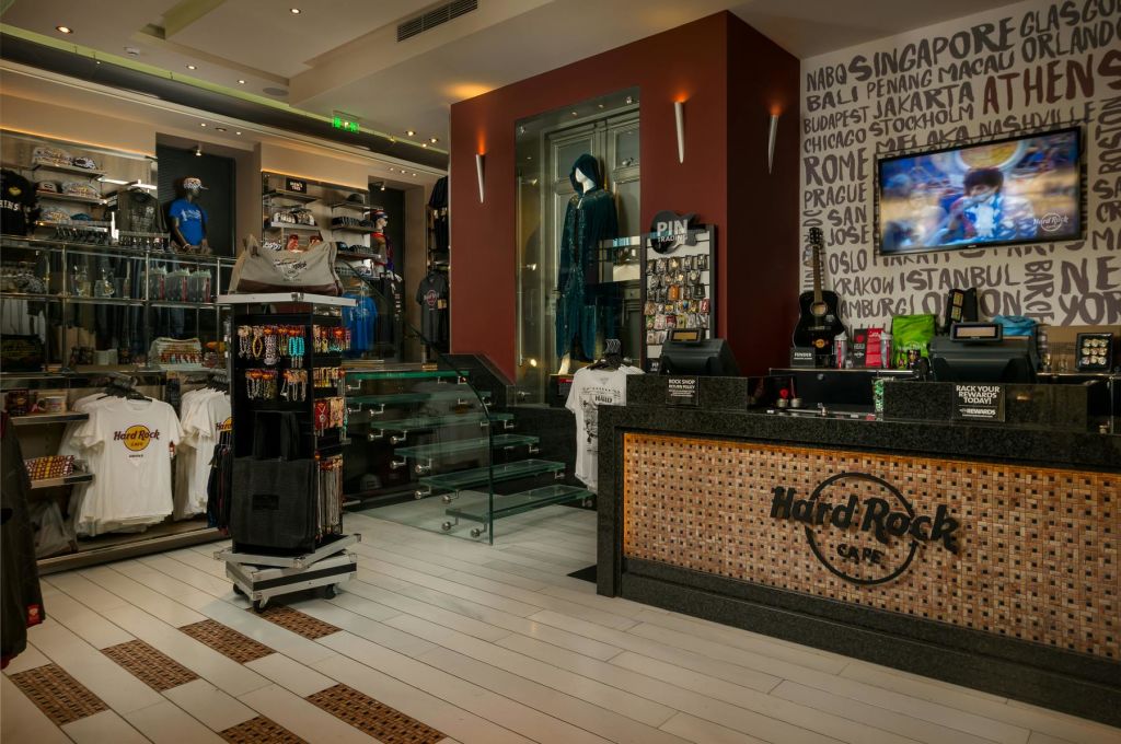 상품이 진열된 하드록 카페 매장 내부, 파란색 의상이 진열된 진열 케이스, 리셉션 카운터.