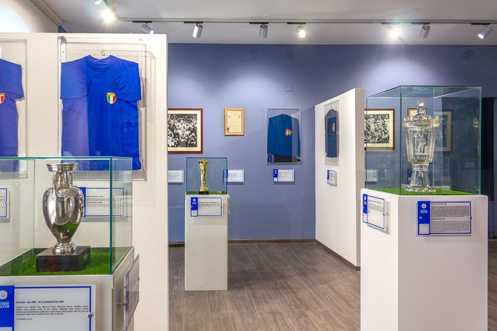 파란색 유니폼, 액자 사진, 유리 케이스의 골드 트로피 등 스포츠 기념품을 전시하는 박물관 전시물입니다.