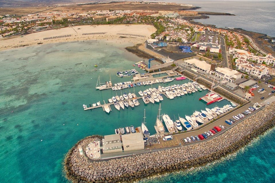 해변과 다양한 건물이 있는 해안 마을에 인접한 수많은 보트가 정박한 정박지의 공중 전망.