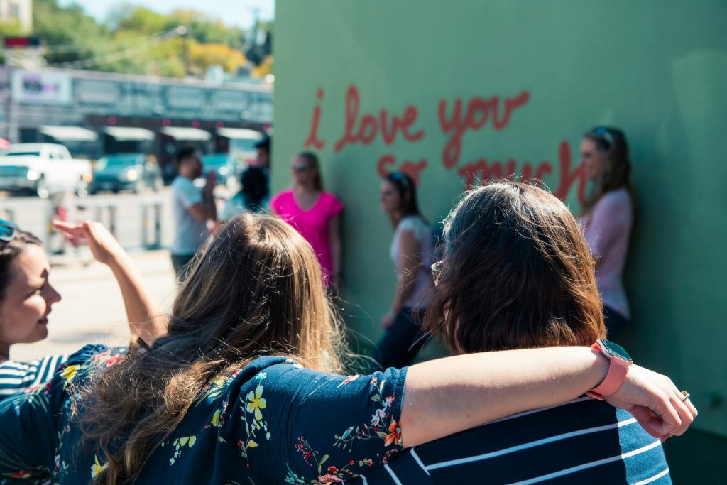 두 사람이 포옹하고 다른 사람들은 벽 근처에 "나는 당신을 너무 사랑합니다" 라고 적힌 포즈를 취합니다.
