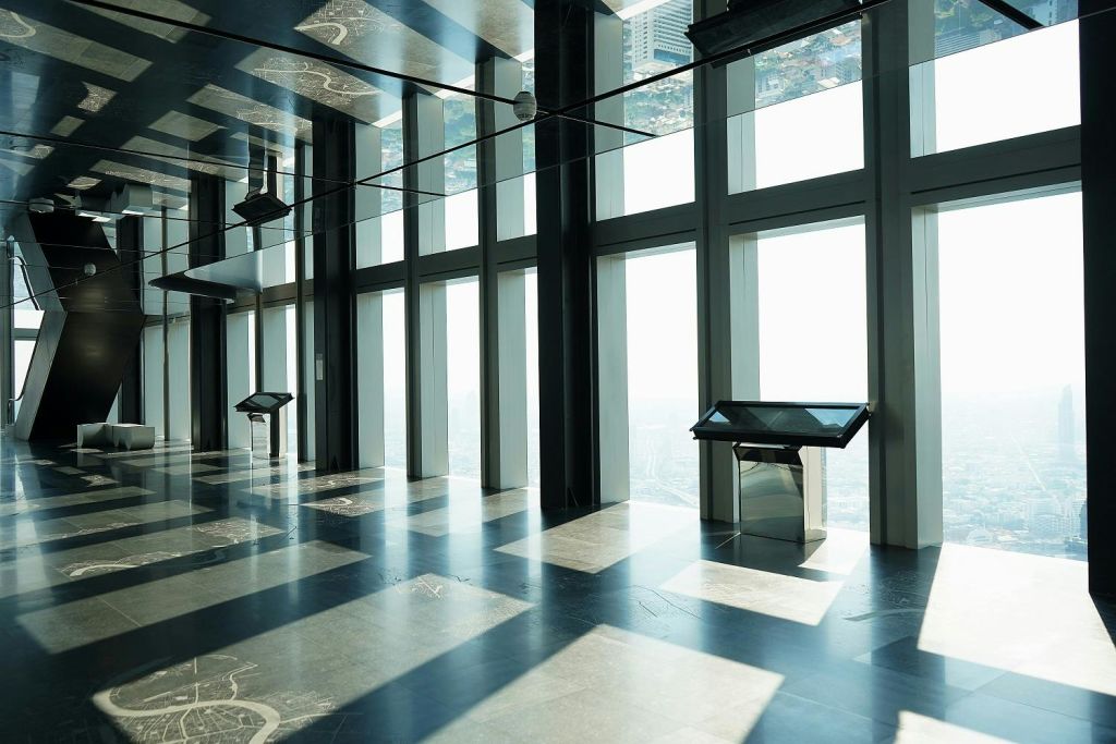 바닥에서 천장까지 이어지는 대형 창문, 도시 풍경, 터치스크린 키오스크가 있는 햇살이 비치는 전망대.