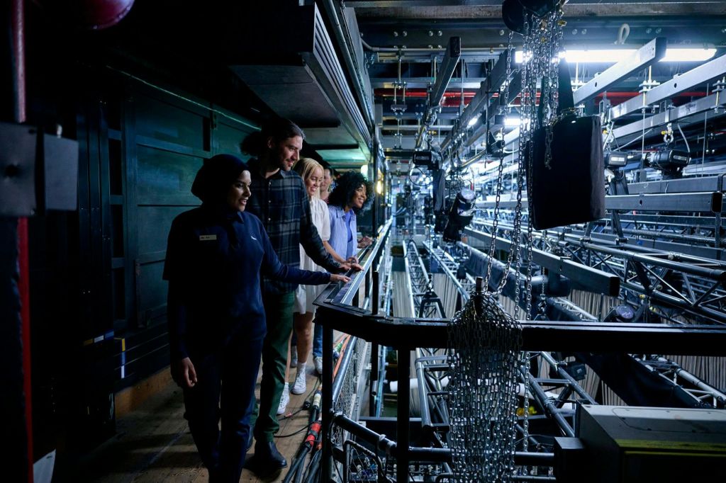 무대 뒤에서 가이드를 따라 극장 조명 인프라를 내려다보는 방문객들