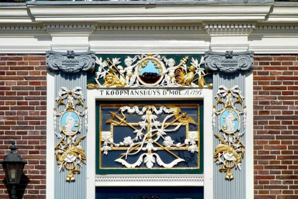 정교한 조각, 기둥, 금색 액센트로 장식된 외관. 비문에는 "T KOOPMANSHUYS D'MOL 1795" 가 적혀 있습니다.