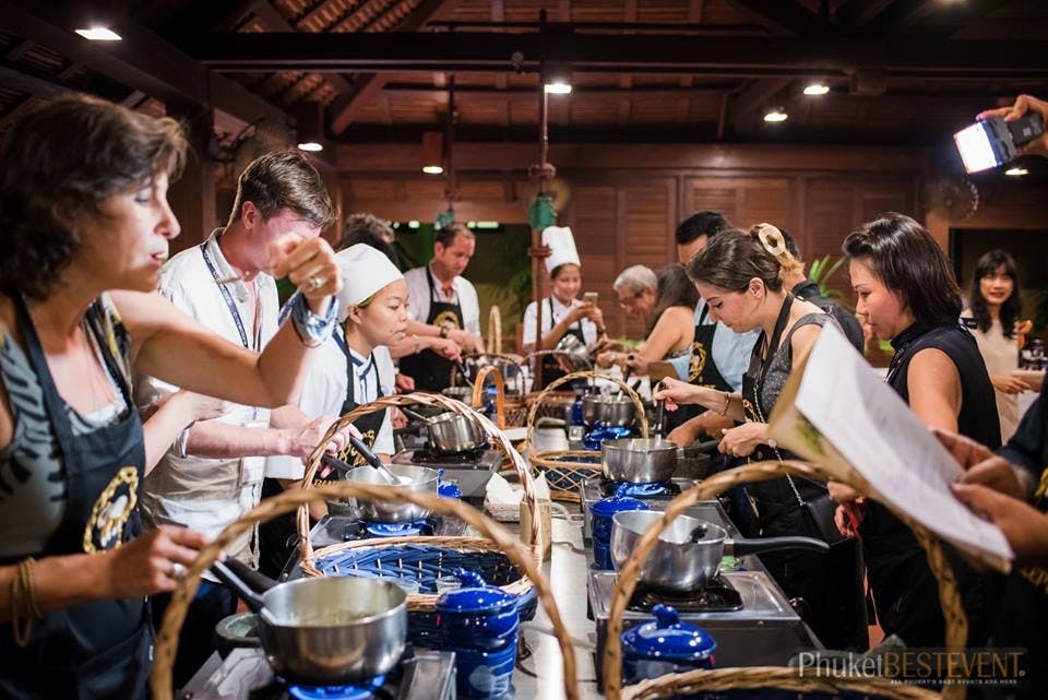요리 수업에 참여하는 사람들은 앞치마와 셰프 모자를 쓰고 뜨거운 접시와 주방 기구를 사용합니다.