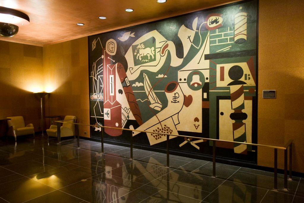 조명이 밝고 현대적인 실내 공간의 벽에 기하학적 모양과 다양한 기호가 있는 화려하고 추상적인 벽화.