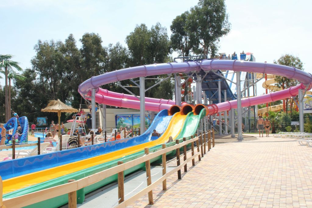 나무와 포장된 산책로로 둘러싸인 야외 워터파크에서 다채로운 워터 슬라이드를 즐겨보세요.