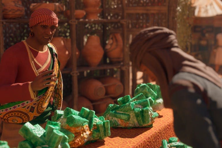 형형색색의 복장을 한 사람이 초록색 미네랄 바위가 놓인 테이블 뒤에 서 있으며, 배경에는 선반에 도자기가 진열되어 있습니다.