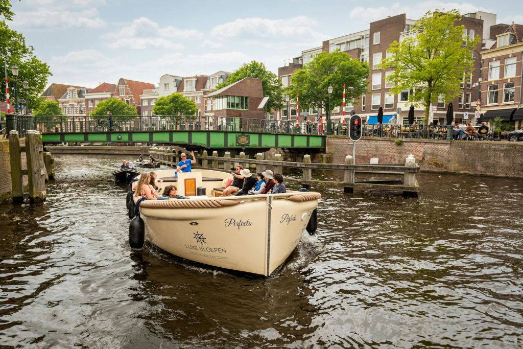 녹색 다리와 주거용 건물을 배경으로 운하에서 보트를 타는 사람들.