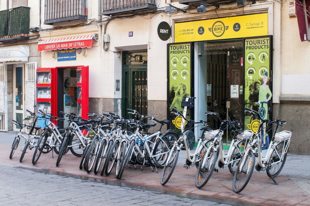 '자전거' 라고 쓰인 표지판이 있는 상점과 근처에 빨간 천막이 있는 또 다른 상점이 있는 상점 밖에서 자전거를 대여할 수 있습니다.