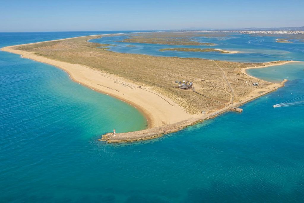 청록색의 맑은 바다, 작은 부두, 밝은 파란색 아래 경치 좋은 해안 풍경이 있는 사막 섬의 공중 전망