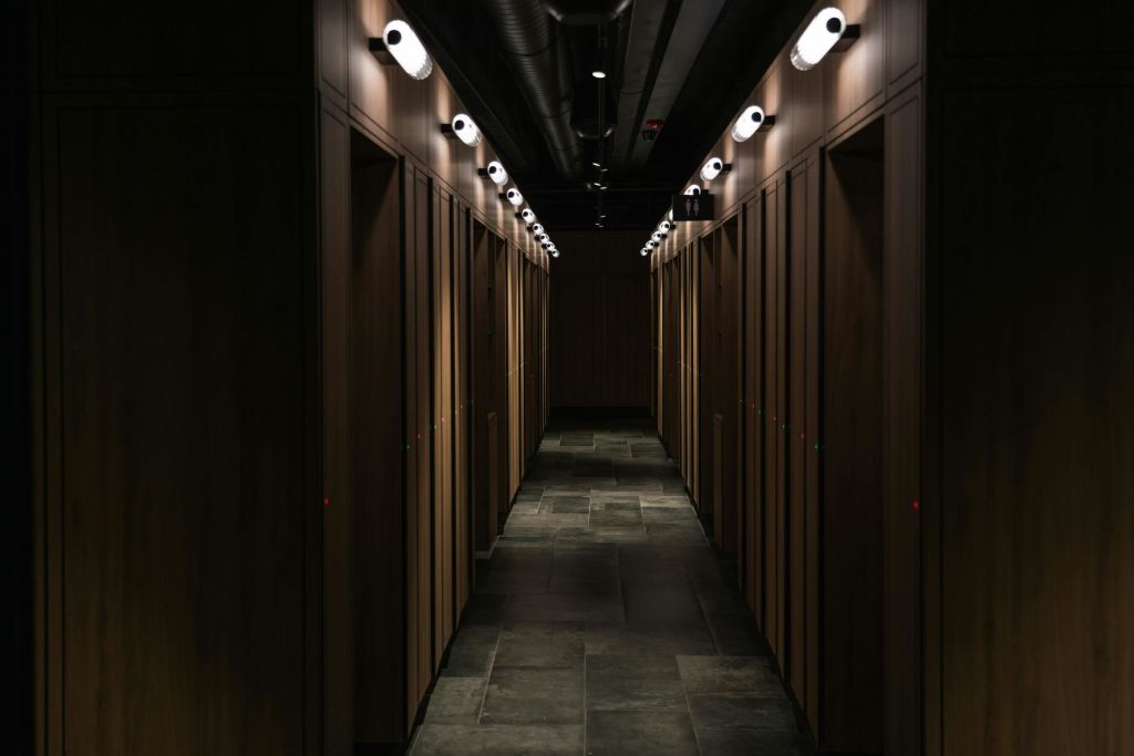 양쪽에 나무 사물함이 있고 머리 위 조명이 있는 희미한 조명 복도.