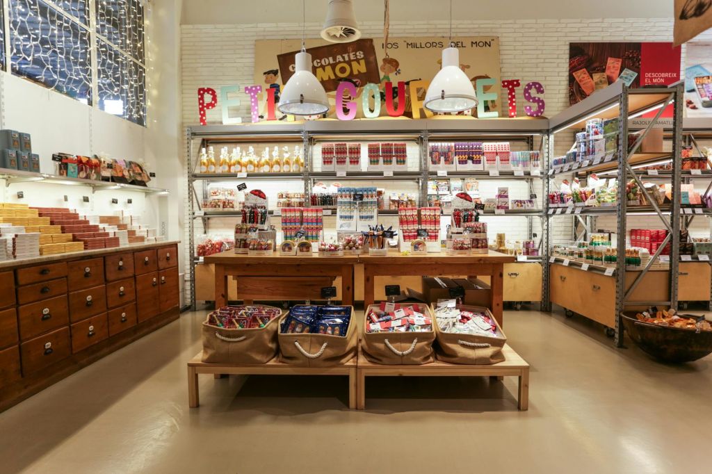 초콜릿과 과자, 나무 테이블, 머리 위로 커다란 걸이 조명이 놓인 다채로운 캔디 스토어 진열대.