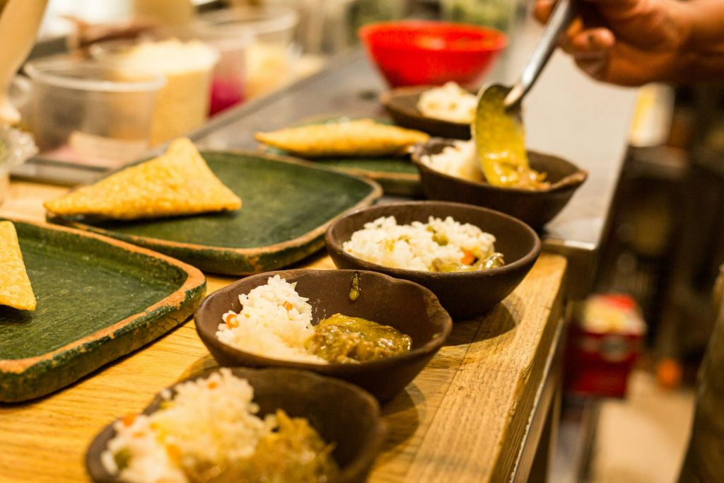 나무 카운터에 접시와 음식이 놓인 밥과 그린 소스 그릇이 준비되어 있습니다.