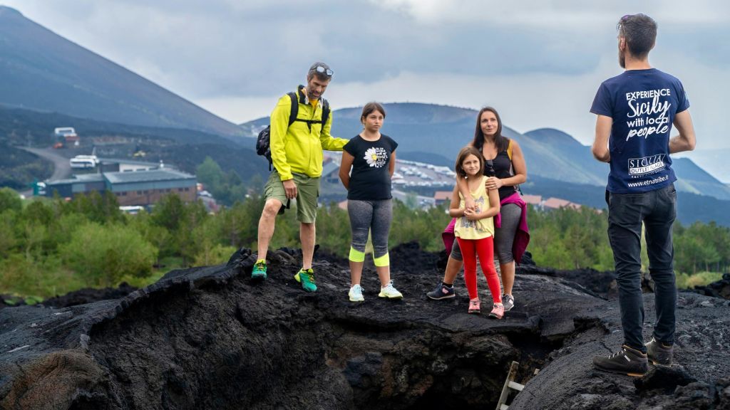 먼 언덕과 흐린 하늘 아래 보이는 주택이 있는 바위 지형에 5인 가족이 서 있습니다.