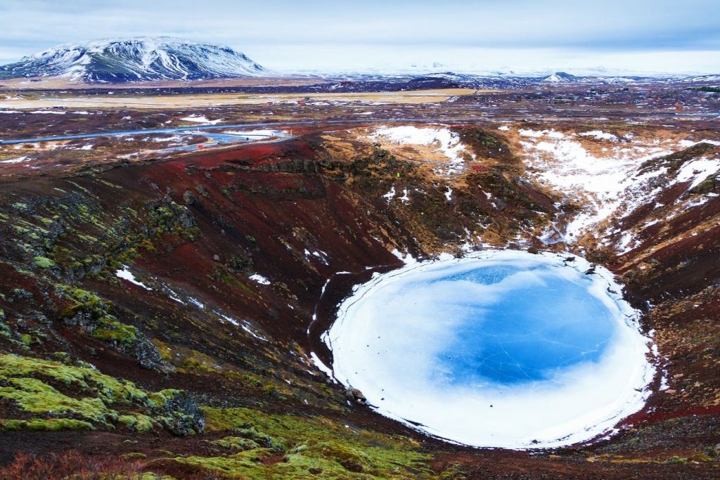 산을 배경으로 겨울에 만나는 케리드 분화구 눈, 녹색 이끼, 붉은 바위.
