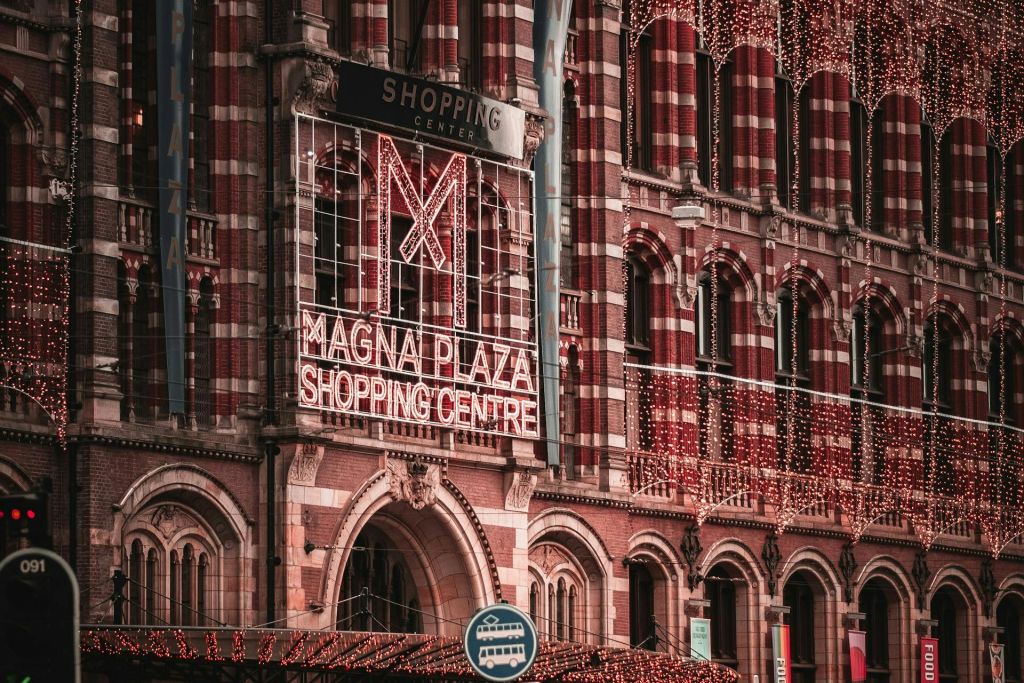 밝은 장식과 앞에 버스 정류장 표지판이 있는 마그나 플라자 쇼핑 센터의 벽돌 외관.