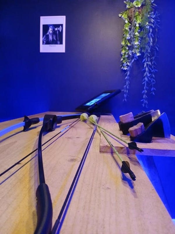 활 두 개와 태블릿이 놓인 나무 테이블의 클로즈업. 배경의 벽에는 식물이 걸려 있고 액자에 담긴 사진이 있습니다.