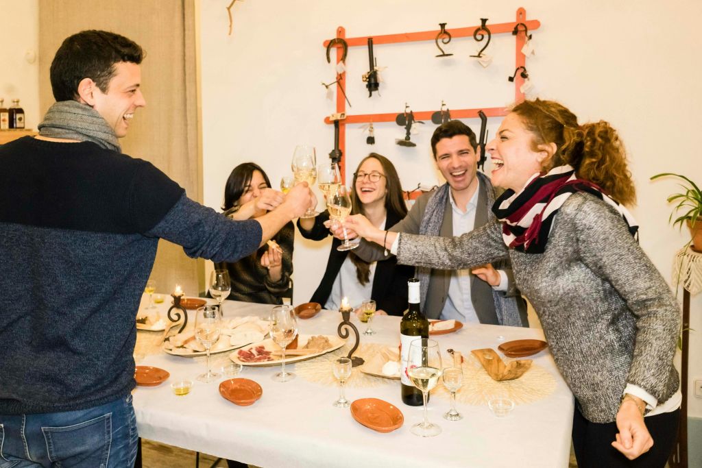 네 명이 웃으며 식음료가 놓인 테이블 주위에서 와인잔을 찰칵거리고 있습니다.