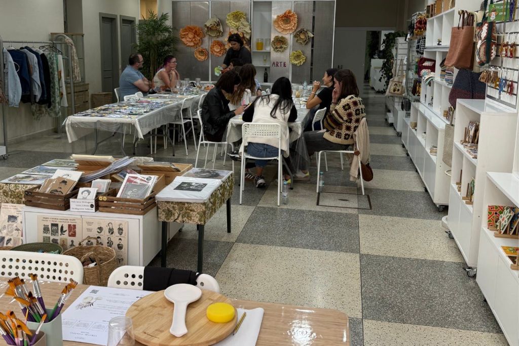 다양한 재료와 장식이 둘러싸인 공예 공방의 테이블에 앉아 있는 사람들의 모임.