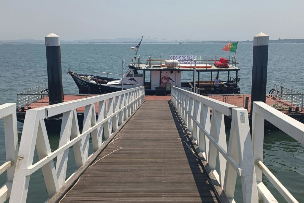 목조 부두 끝에 있는 도킹 투어 보트로, 경사로가 이어집니다. 이 보트에는 국기와 승객이 타고 있습니다.