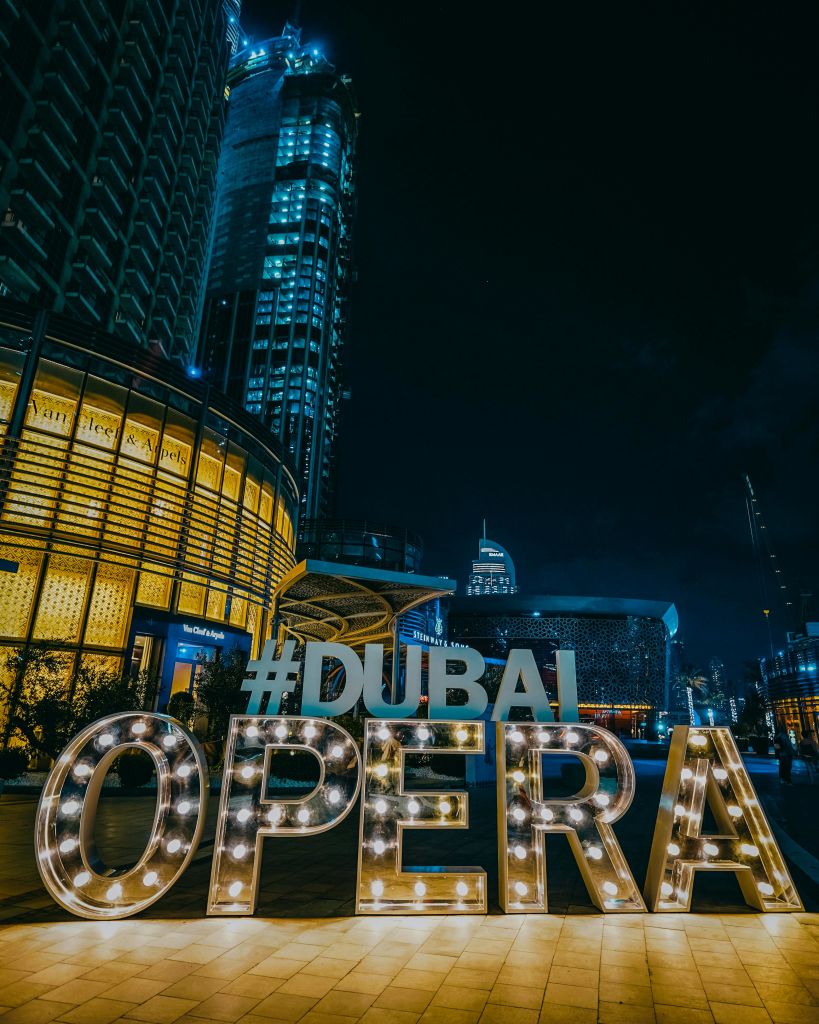 야간에는 조명이 켜진 건축물과 고층 건물을 배경으로 "두바이 오페라" 간판에 불이 들어옵니다.