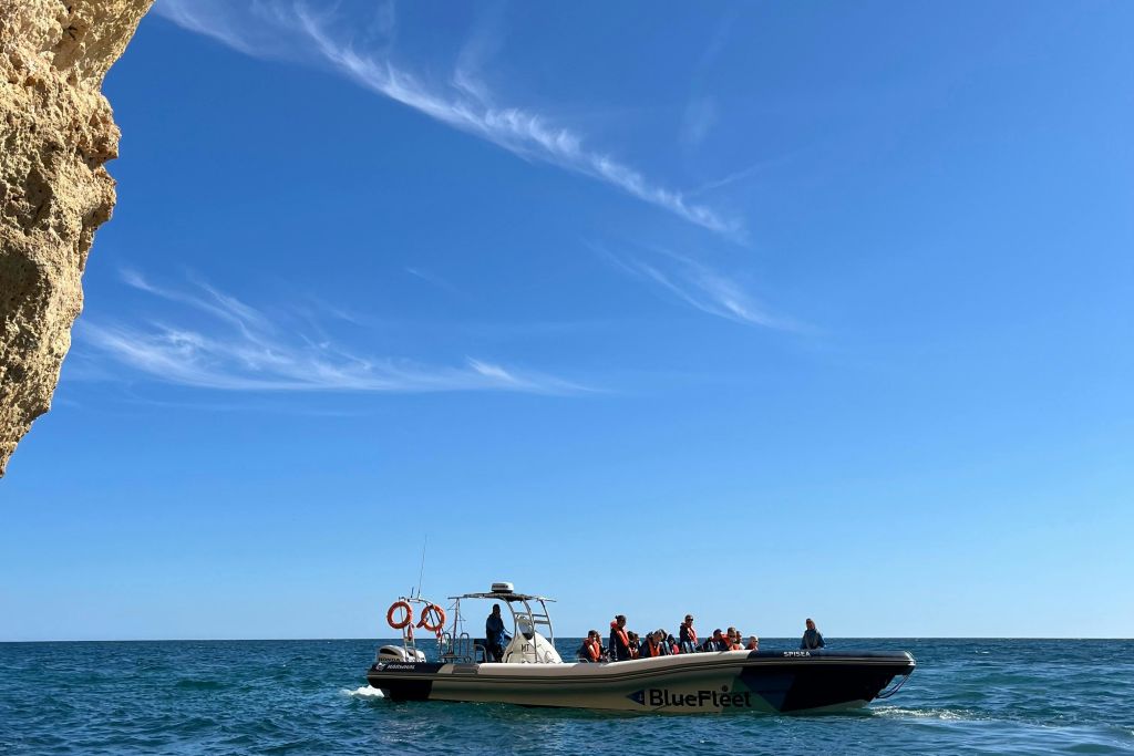 맑고 푸른 하늘 아래 잔잔한 바다에서 구명조끼를 입은 승객들이 탑승한 '블루 플리트 (Blue Fleet)' 라는 이름의 모터보트.