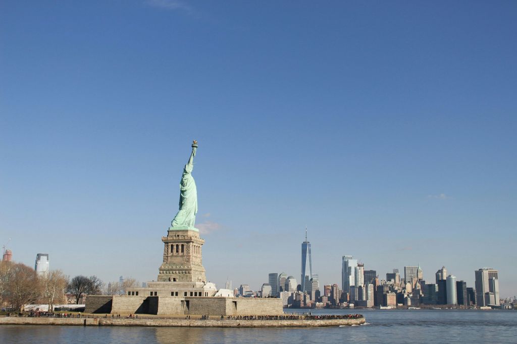 자유의 여신상은 원 월드 트레이드 센터를 포함한 뉴욕의 스카이라인을 배경으로 자유의 섬에 서 있습니다.