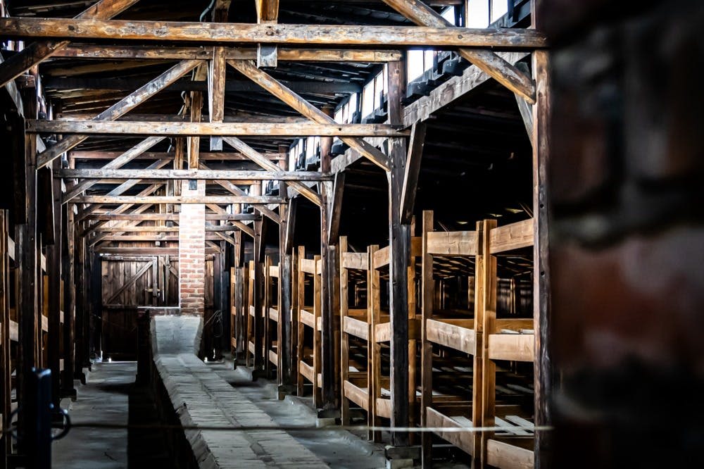 어두운 조명의 오래된 목조 건물 내부에는 수많은 목조 이층 침대와 중앙에 통로가 있습니다.
