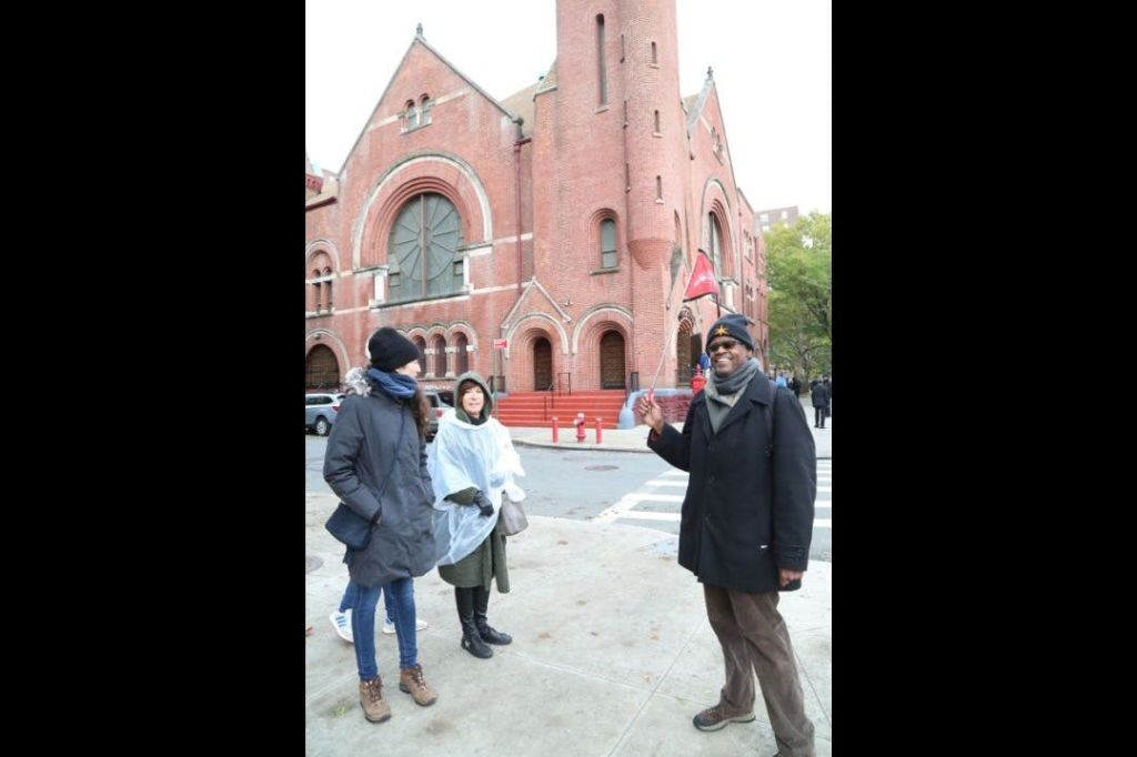 할렘의 상징적인 교회 앞에 자랑스럽게 서 있는 투어 가이드의 생동감 넘치는 사진.