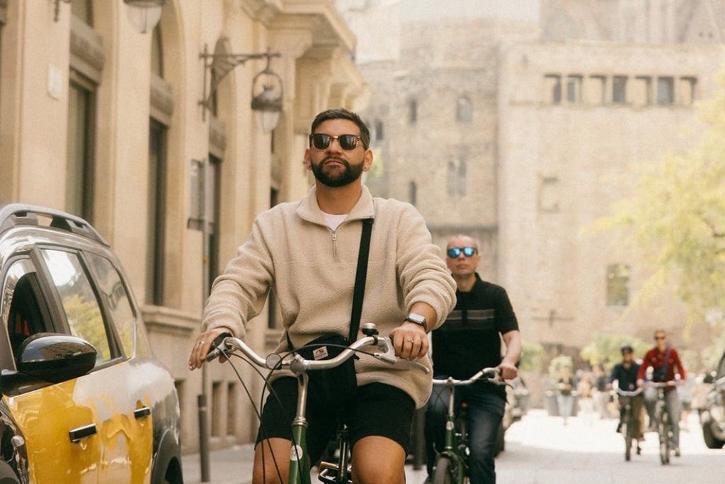 화창한 날 유서 깊은 건물이 있는 거리에서 자전거를 타는 두 사람.